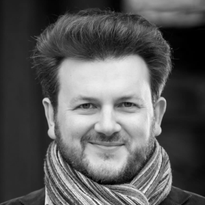 A man with dark hair wearing a scarf.