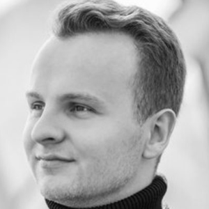 A man with short blonde hair wearing a turtle neck.