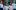 A group of children singing. They are all wearing blue polo shirts with the Opera North logo on them.
