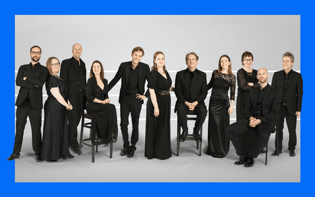 A group of eleven men and women dressed in coordinated black outfits smile at the camera
